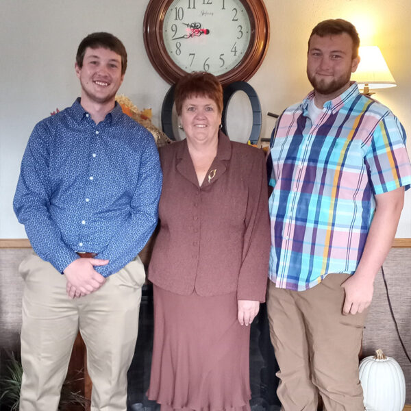 Karen Powell standing in a living room with her two sons.